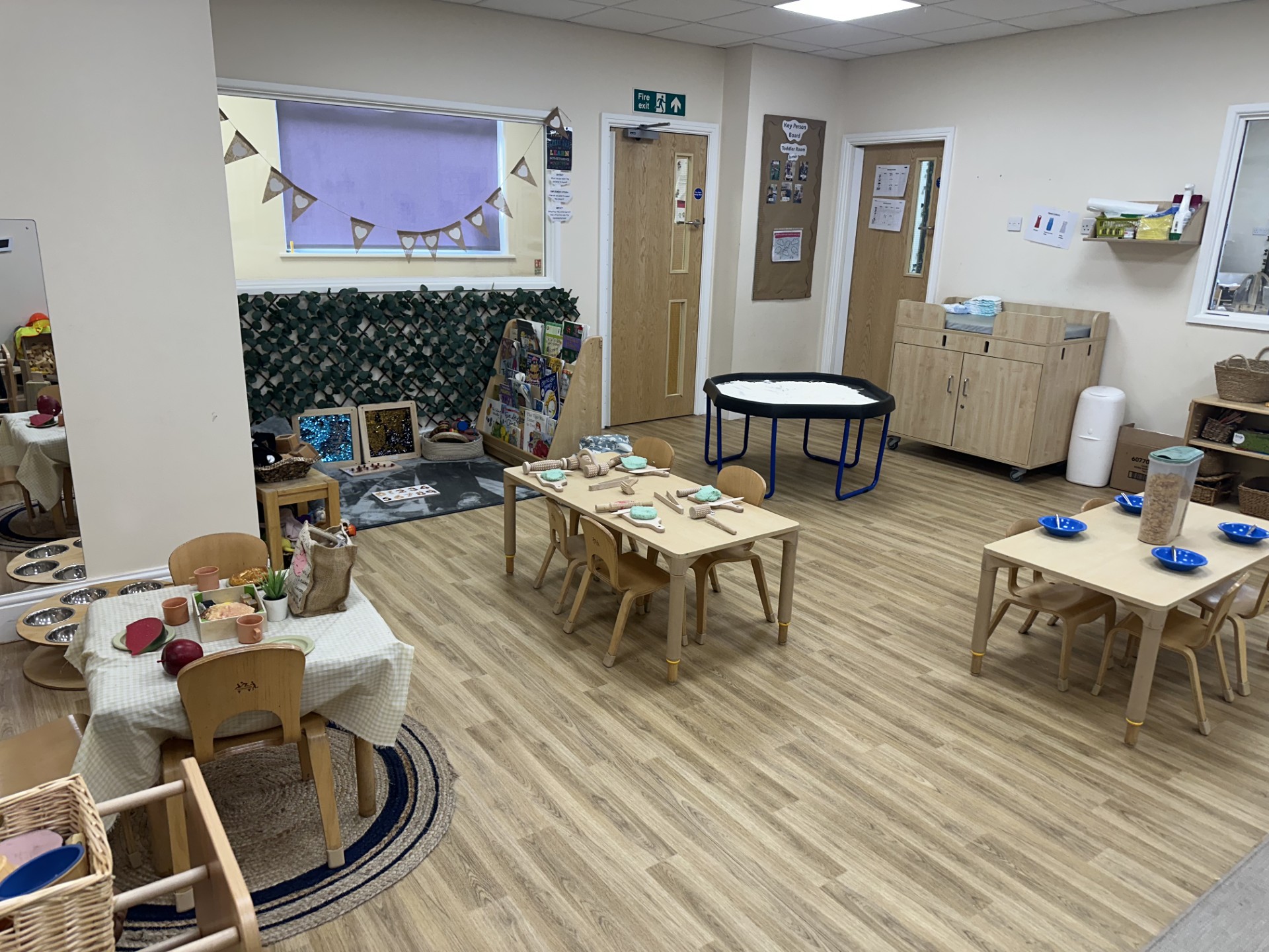 Wooden tables and chairs with sensory activities set up at Partou Upton Day Nursery in Prenton