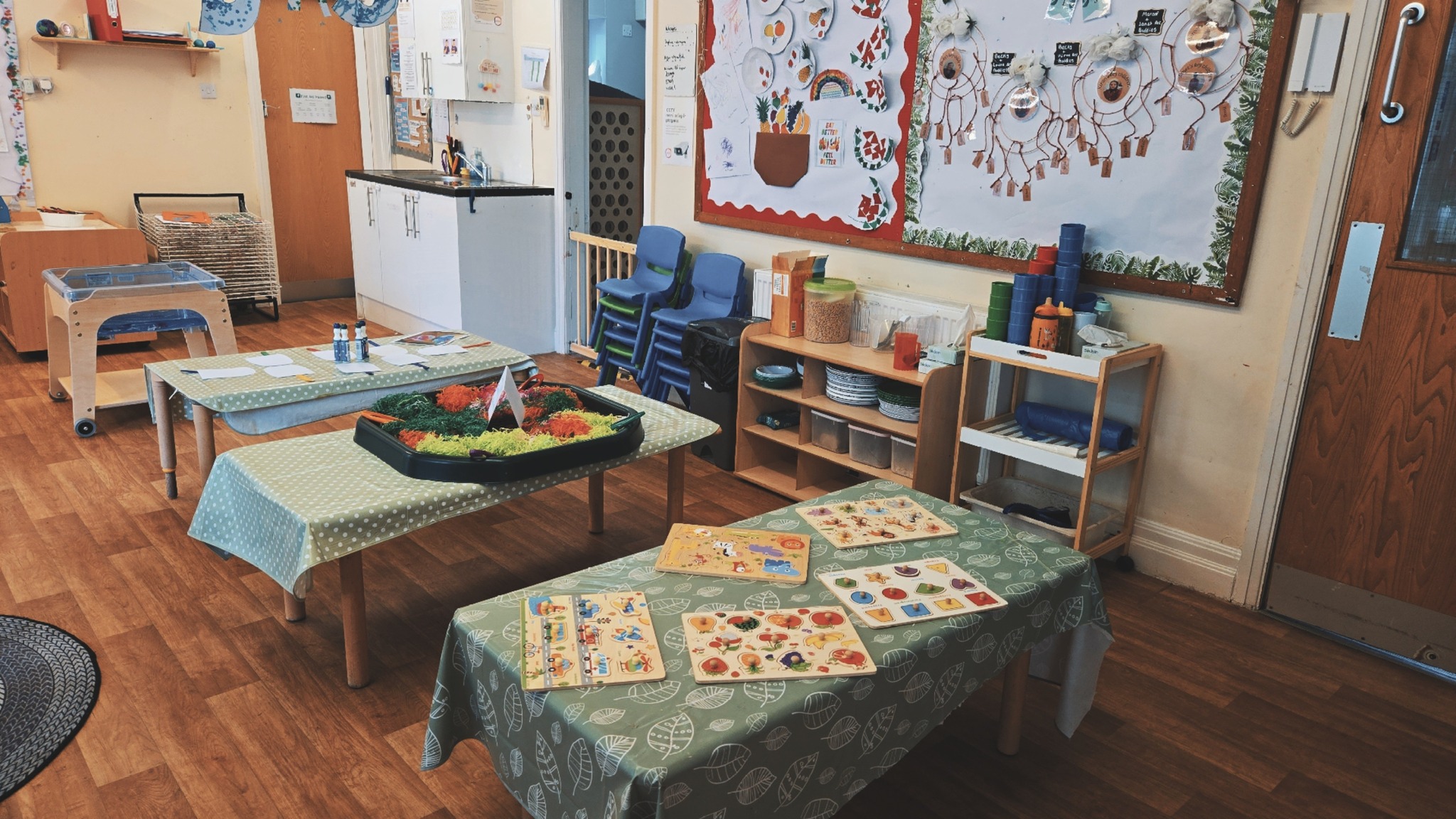 Covered wooden tables with sensory and cognitive development activities on top near children