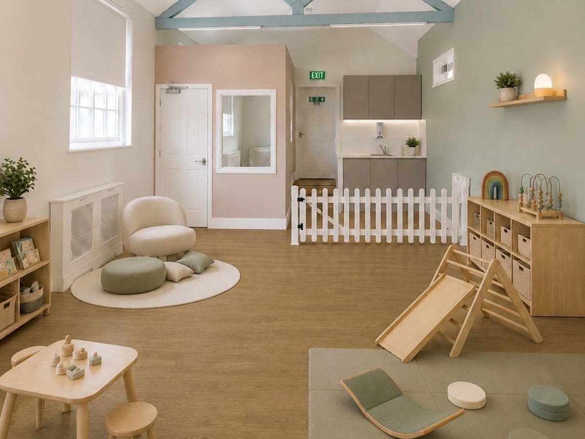 CGI of the new Partou Norwood Day Nursery & Pre-School opening in West Norwood, London in October 2026, showcasing a calm baby room with soft sage green and blush pink walls, natural wood furniture, age-appropriate climbing equipment, cosy seating areas, sensory resources and warm oak-toned flooring. Decor and resources shown are for illustrative purposes.