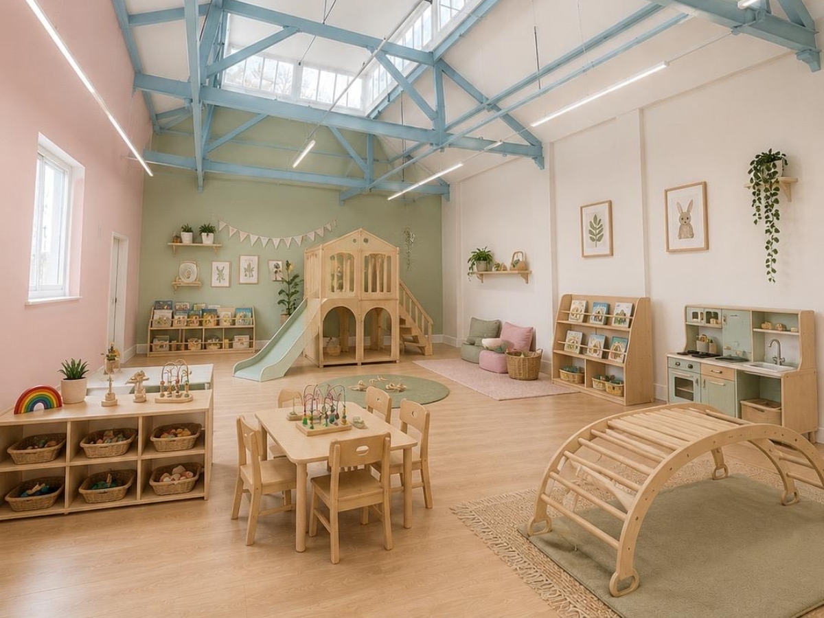 CGI of the new Partou Norwood Day Nursery & Pre-School opening in West Norwood, London in October 2026, featuring a bright early years learning space with soft sage green and blush pink walls, natural wood furniture, a wooden playhouse with slide, cosy book corners, sensory resources and a vaulted ceiling with powder blue beams. Decor and resources shown are for illustrative purposes.