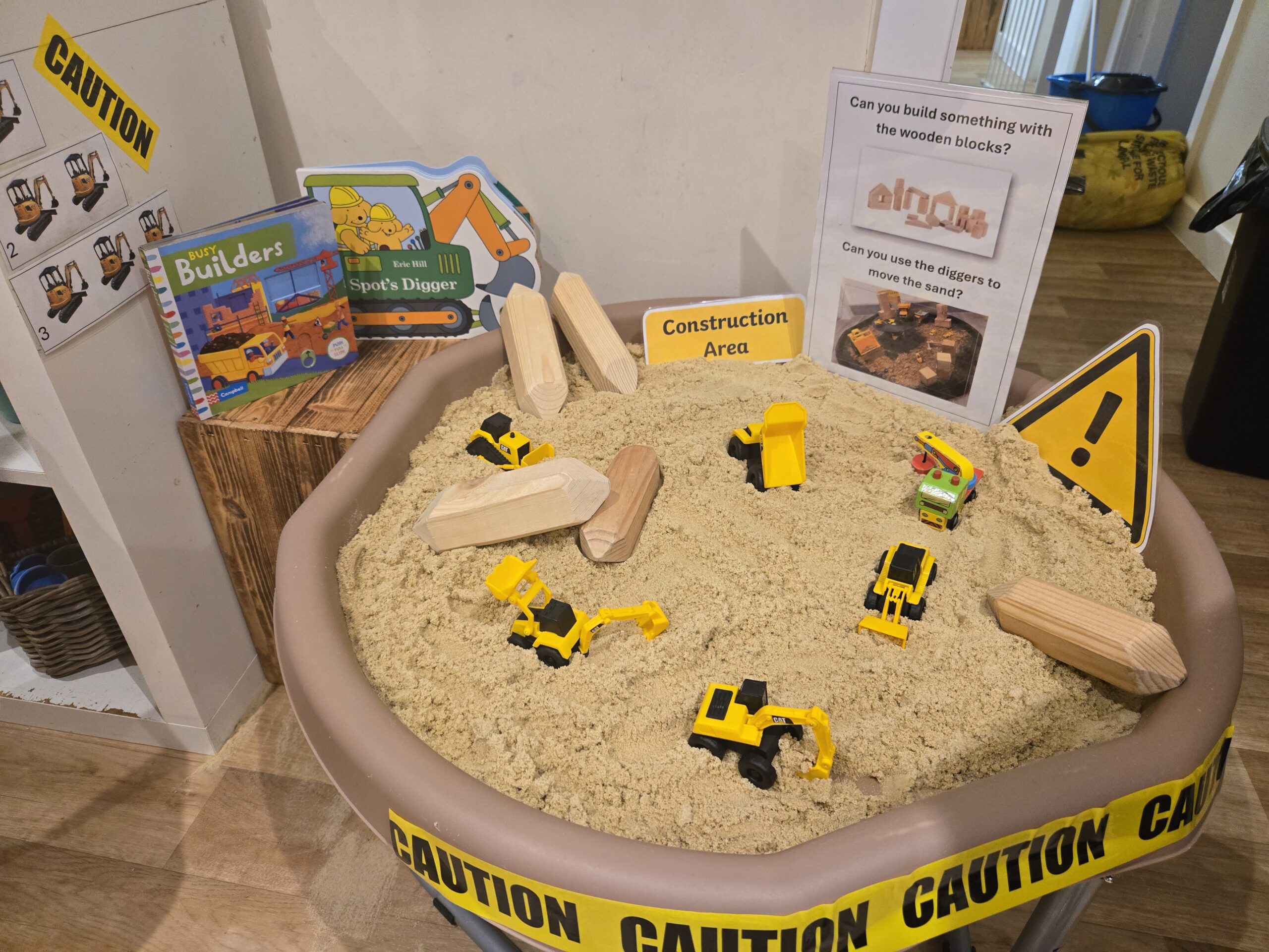 Black andyellow construction vehicle toys in sand at Partou Acorns in Adel nursery and pre-school in Leeds