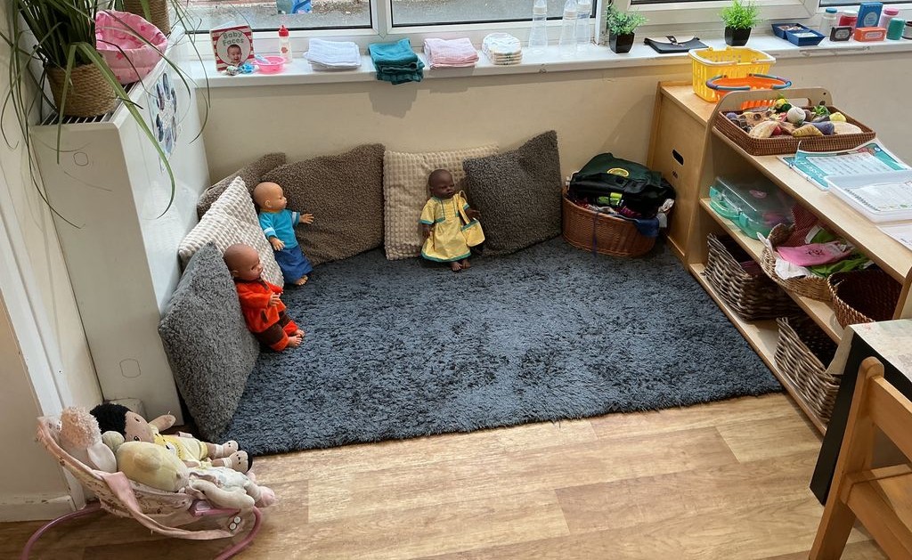 Rug with cushions and dolls next to a window at Partou Acorns in Adel nursery and pre-school in Leeds