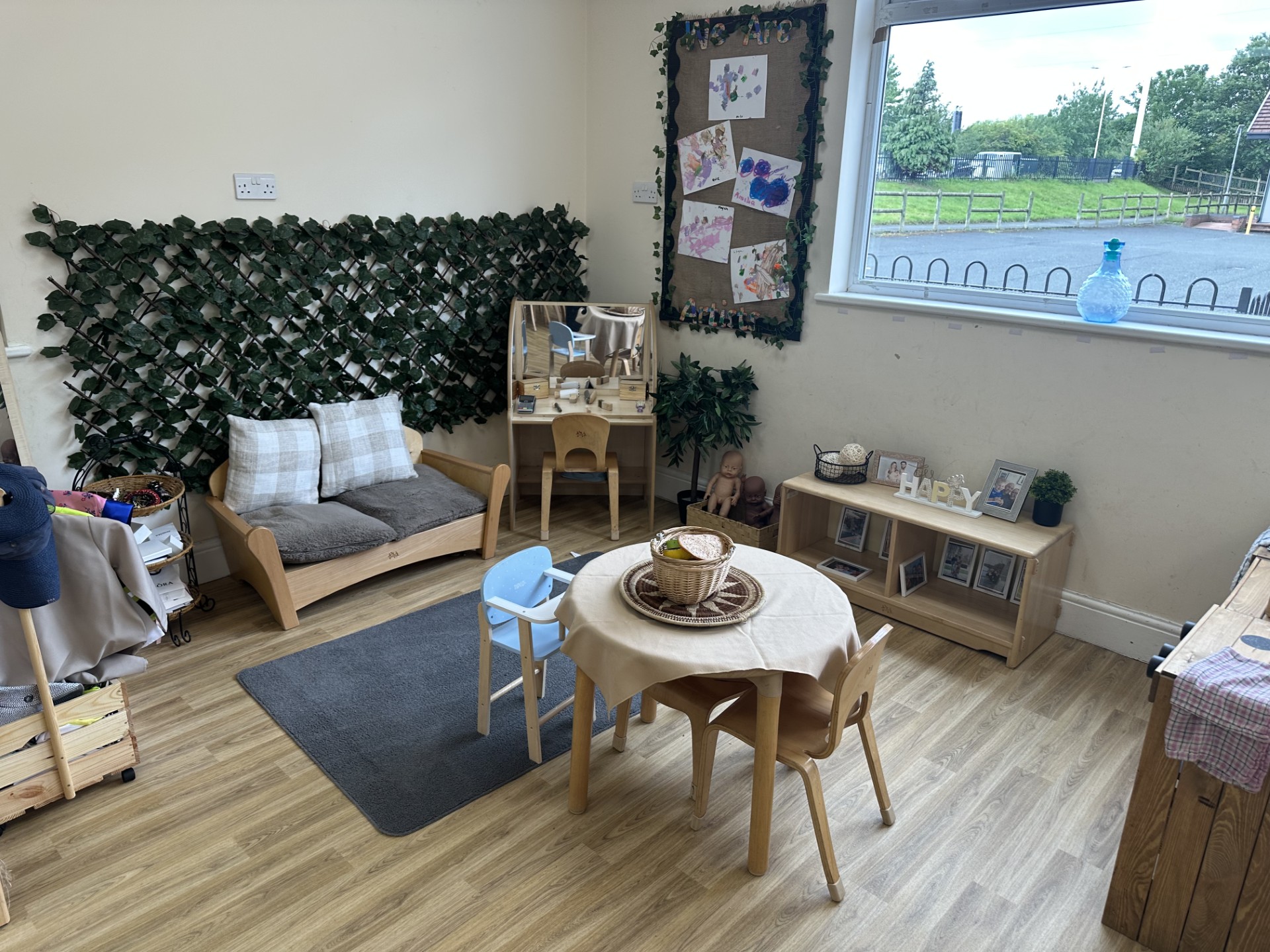 Wooden table and chairs with home role play toys at Partou Upton Day Nursery in Prenton
