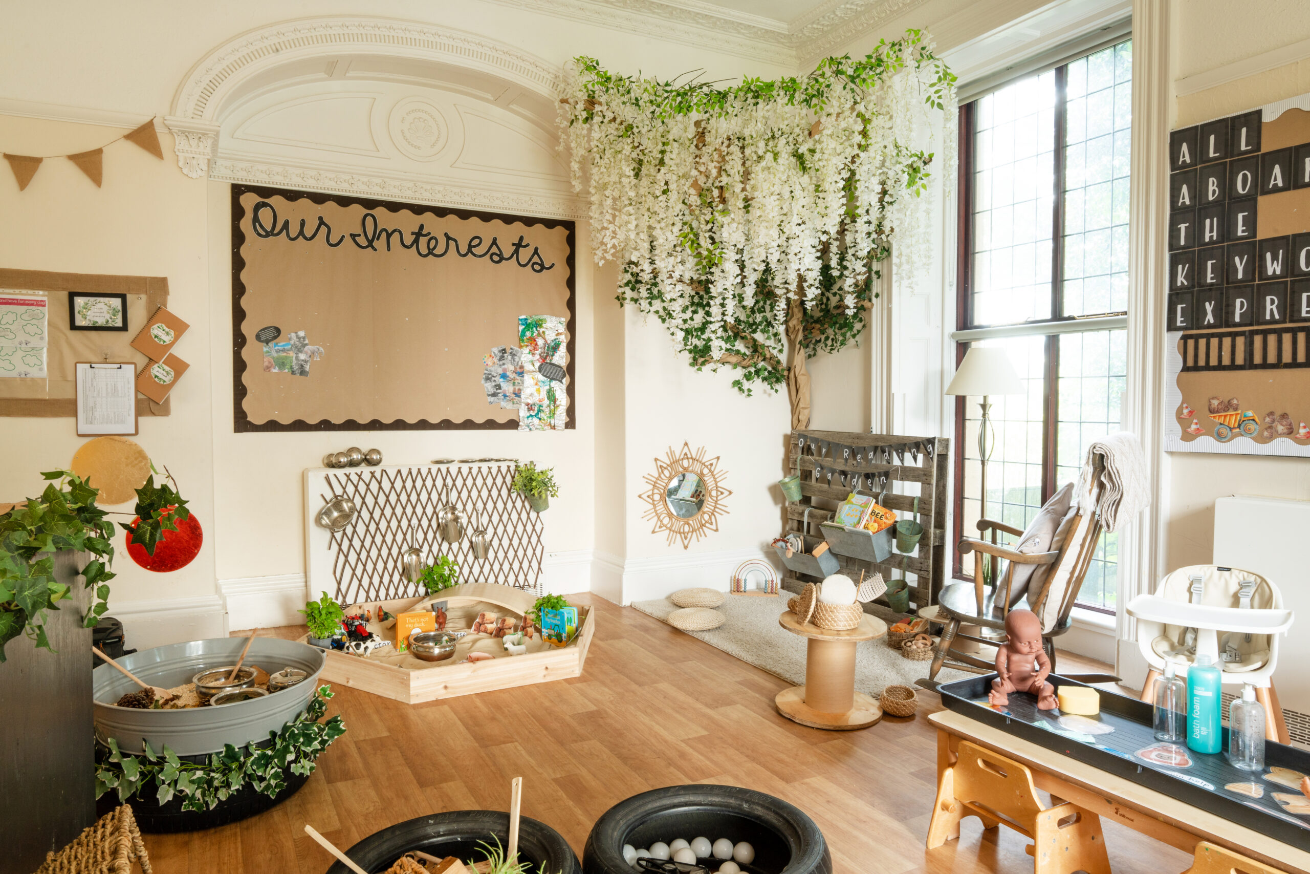 Toddler room at Hilltops nursery in Chorley with sensory toys, books a large crafted tree and light coming in through a large window