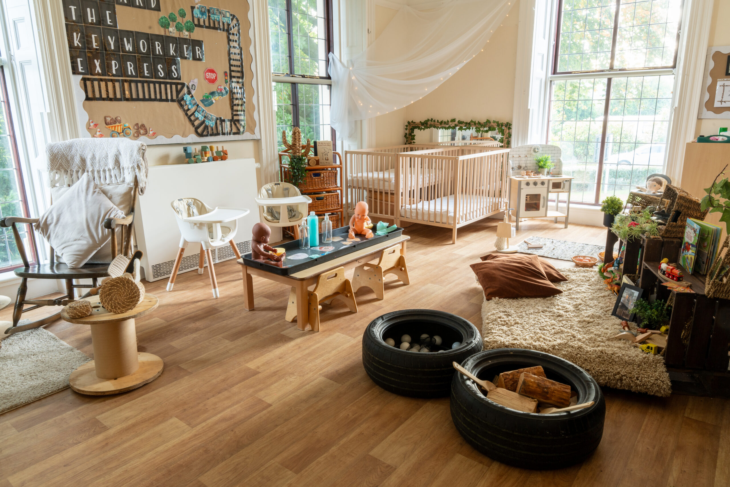 Home from home toy area at Hilltops nursery in Chorley with pretend baby care, rocking chair and cots