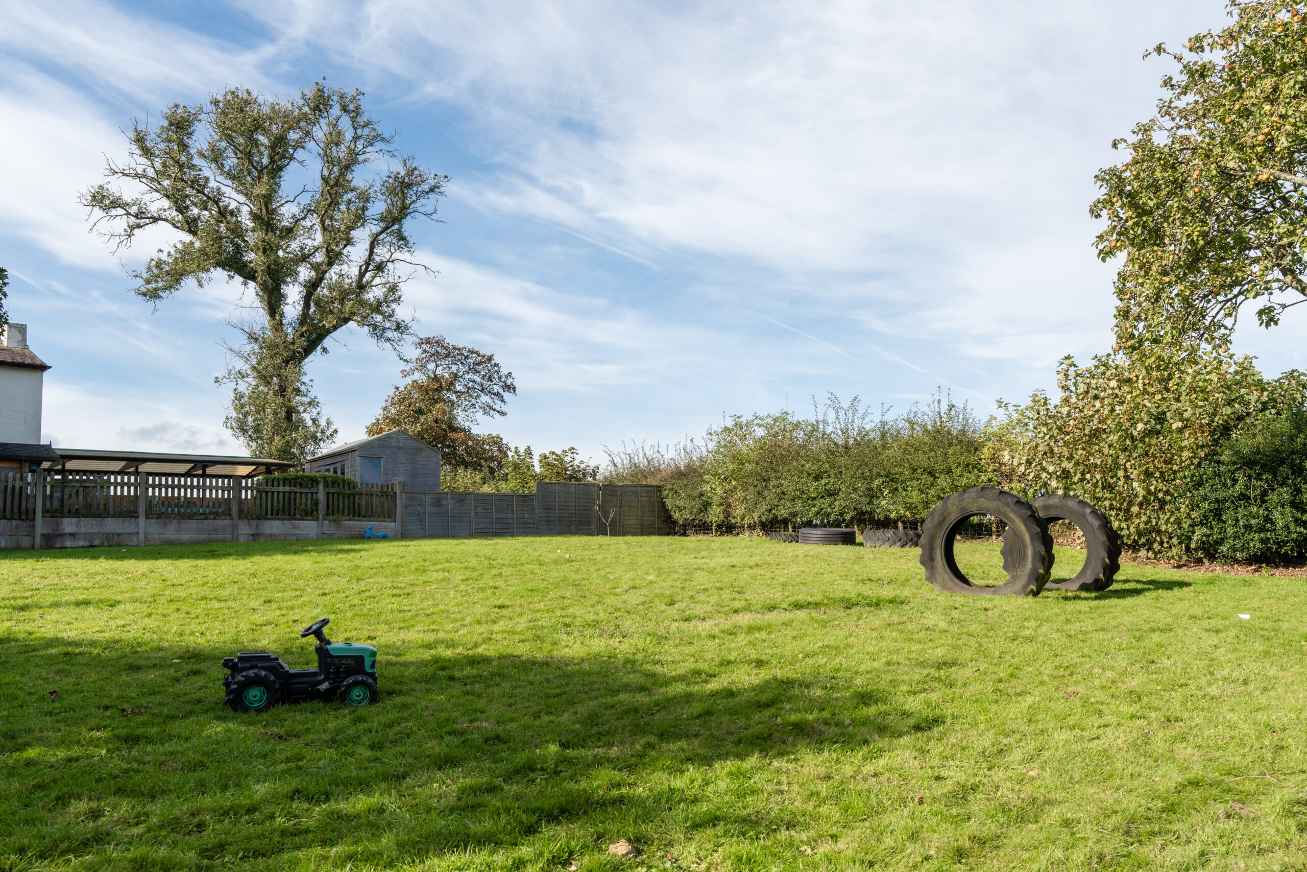 Large green outdoor space with tyres and a small child