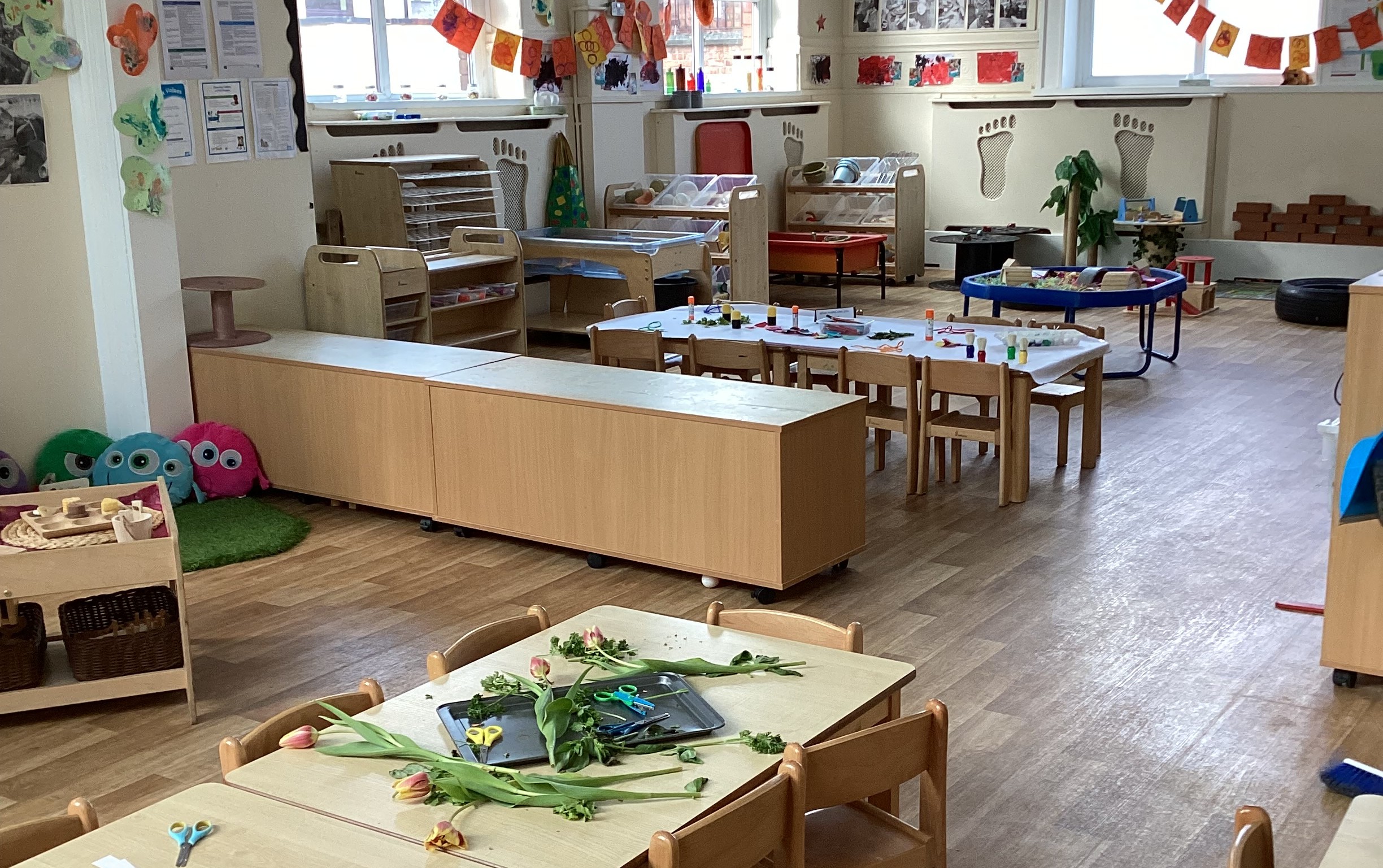 Large hall with tables and chairs and play activities set up at Partou Footprints nursery in Atherton