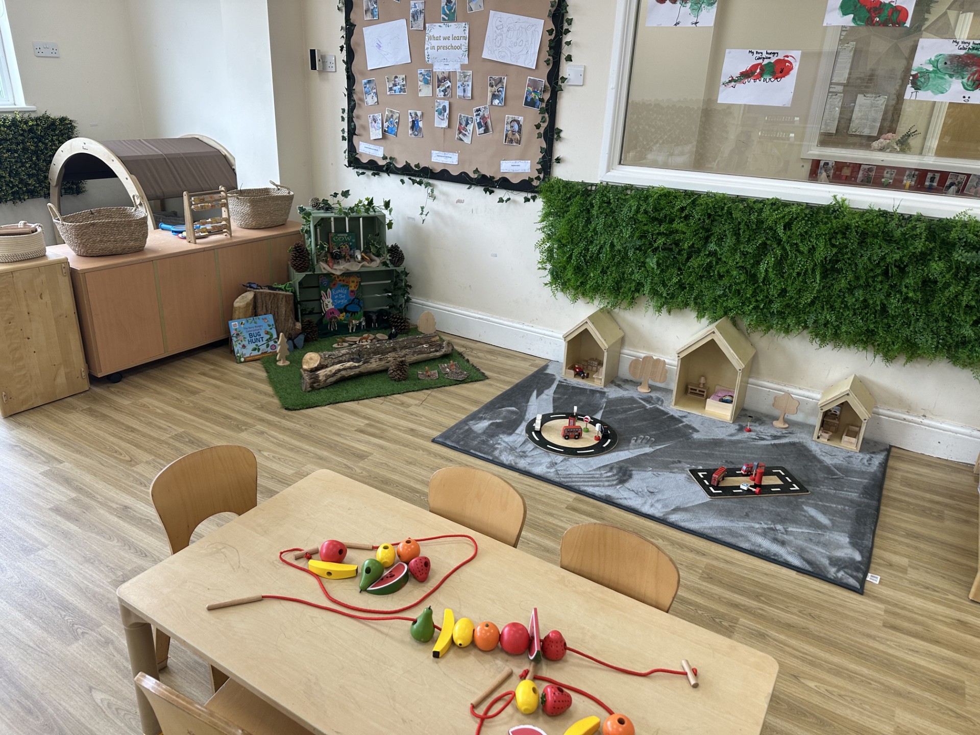Wooden fruit beads threaded onto red string for motor skill development at {Partou Upton Day Nursery in Prenton