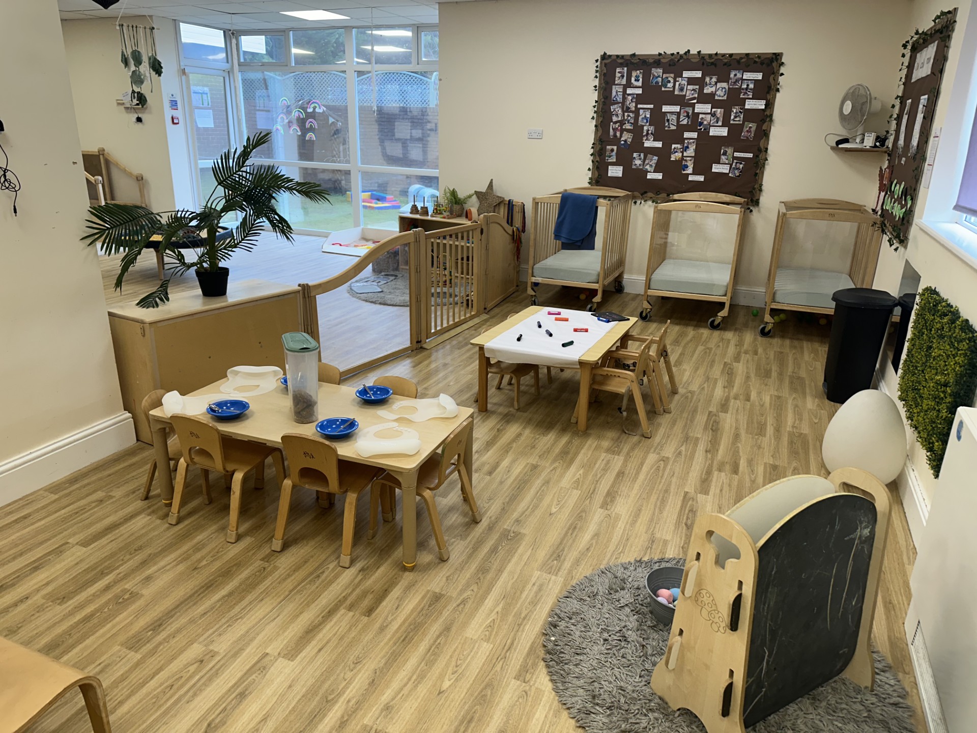 Wooden table and chairs with natural resource material set up for play at Partou Upton Day Nursery