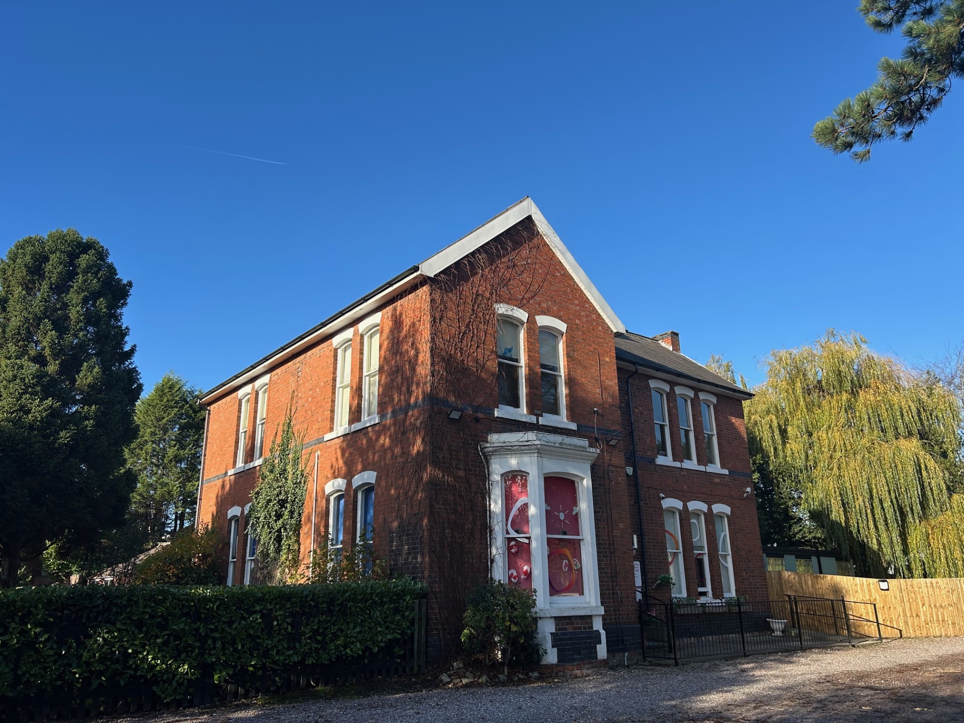 Brick Partou Kids Corner Day Nursery building with white framed windows, bright blue clear sky and gravel drive