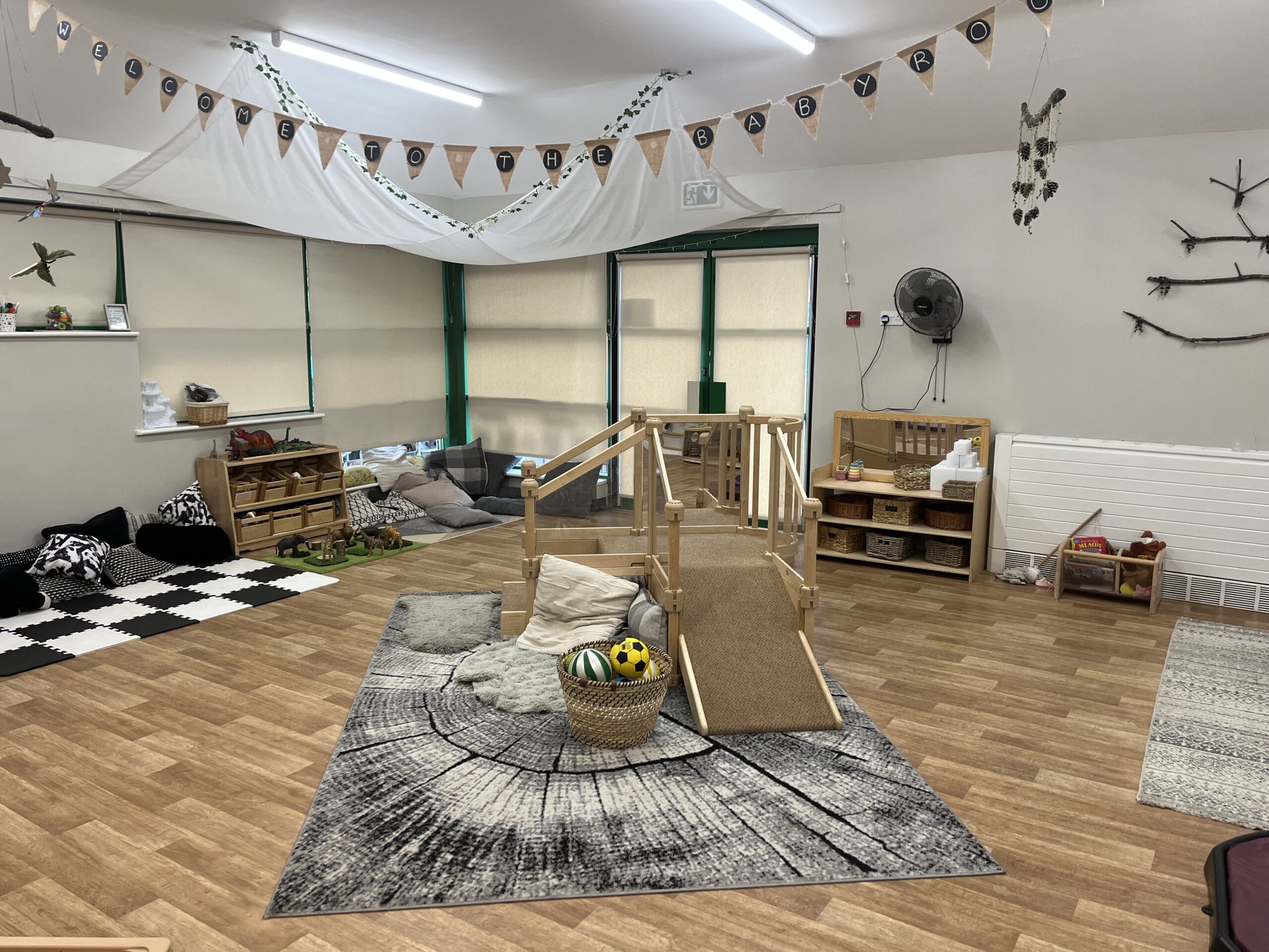 Toddler wooden play structure in the middle of the baby room at Partou Smileys nursery in Stafford