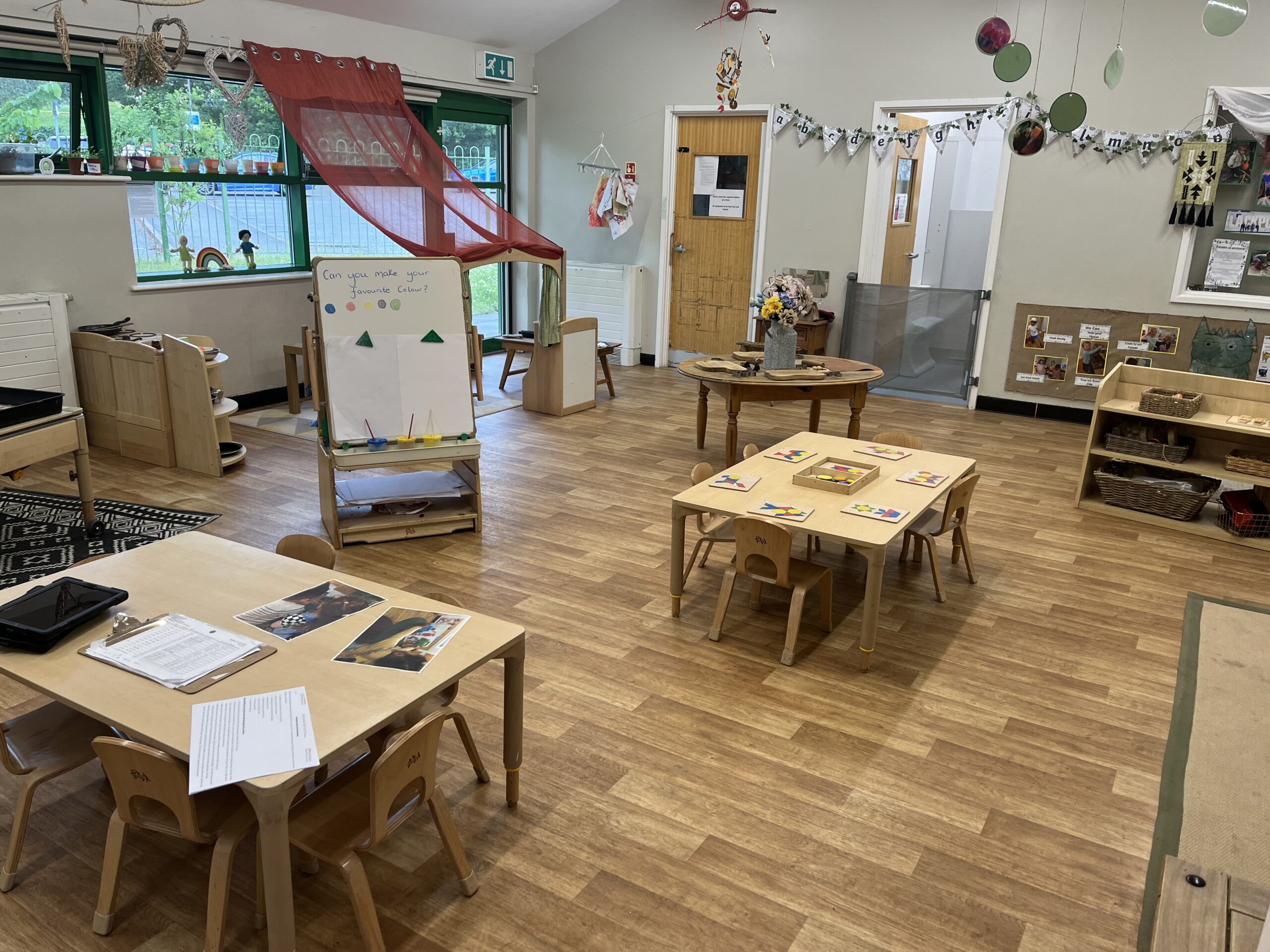 Large neutrally decorated preschool room at Partou Smileys in Stafford with various play activities set up