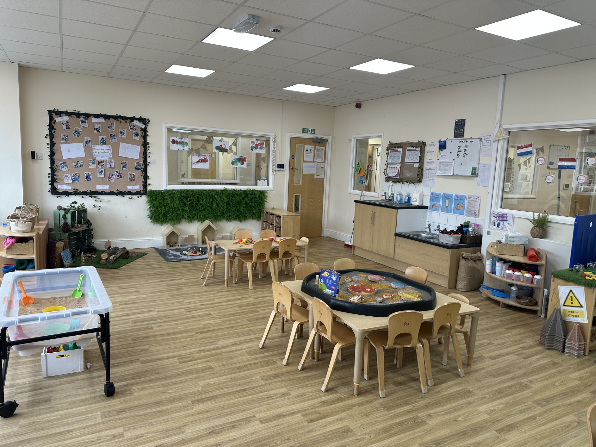 Pre-school room at Partou Upton nursery with tough trays and mark making activities with wooden tables and chairs nearby