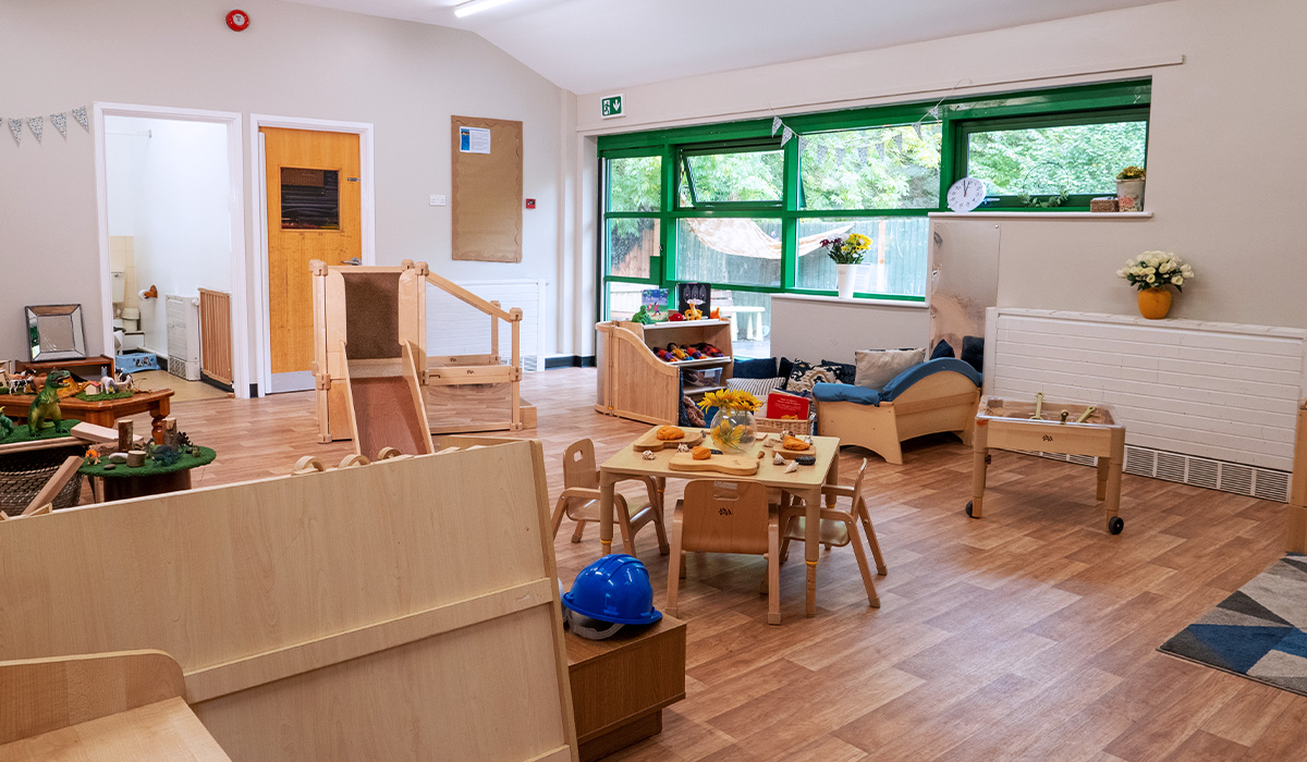 Toddler room at Smileys nursery in Stafford with table, reading areas with sofa and indoor wooden slide