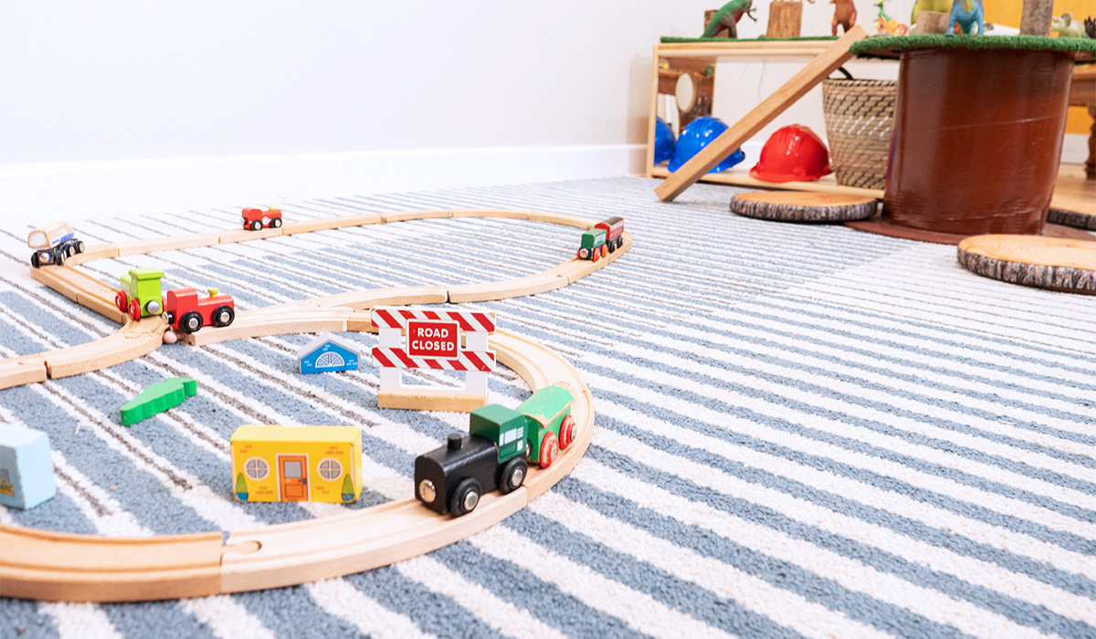 Wooden track and train on a blue and white striped carpet at Smileys nursery in Stafford