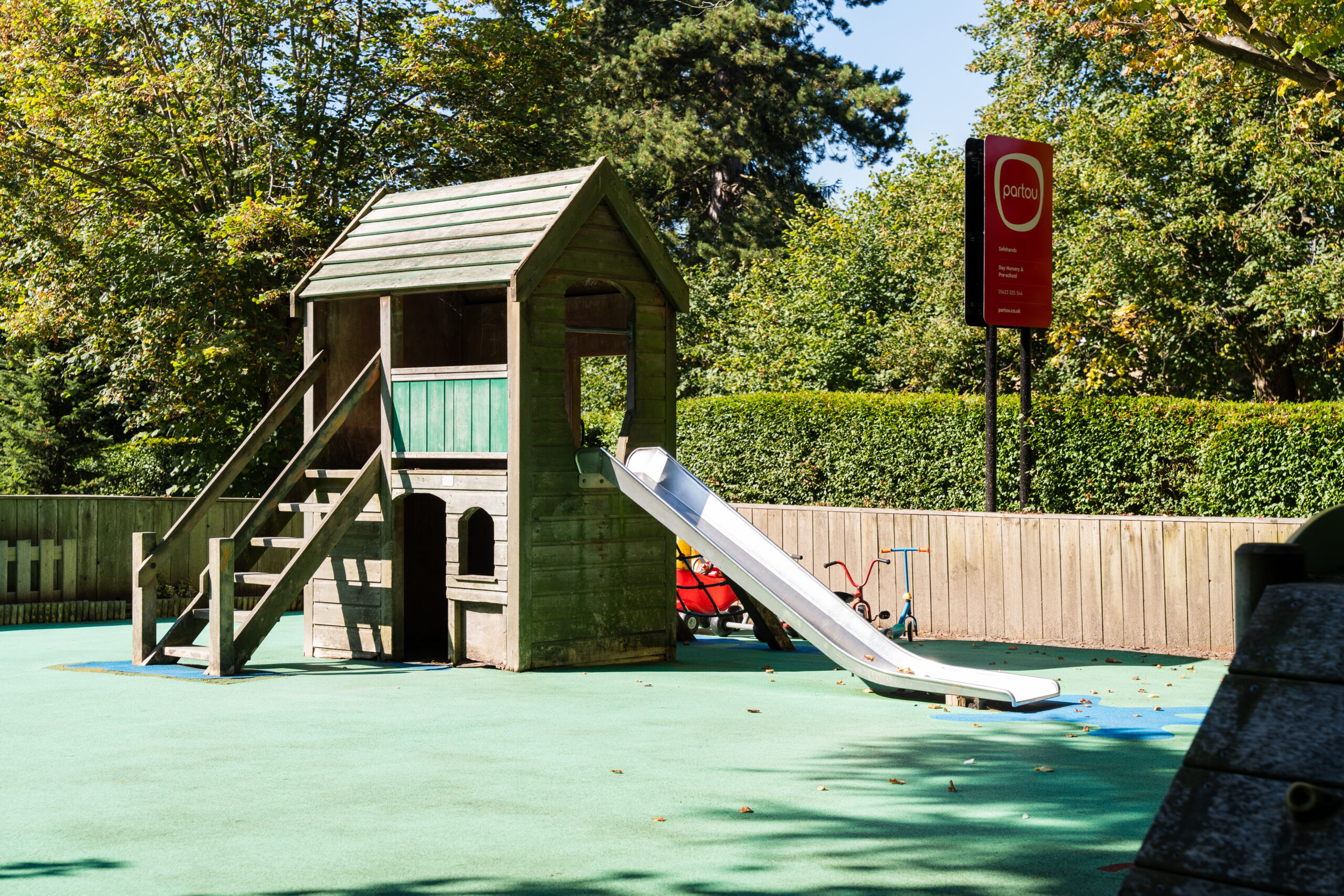 Large wooden playhouse with steps and a slide at Safehands nursery in Harrogate