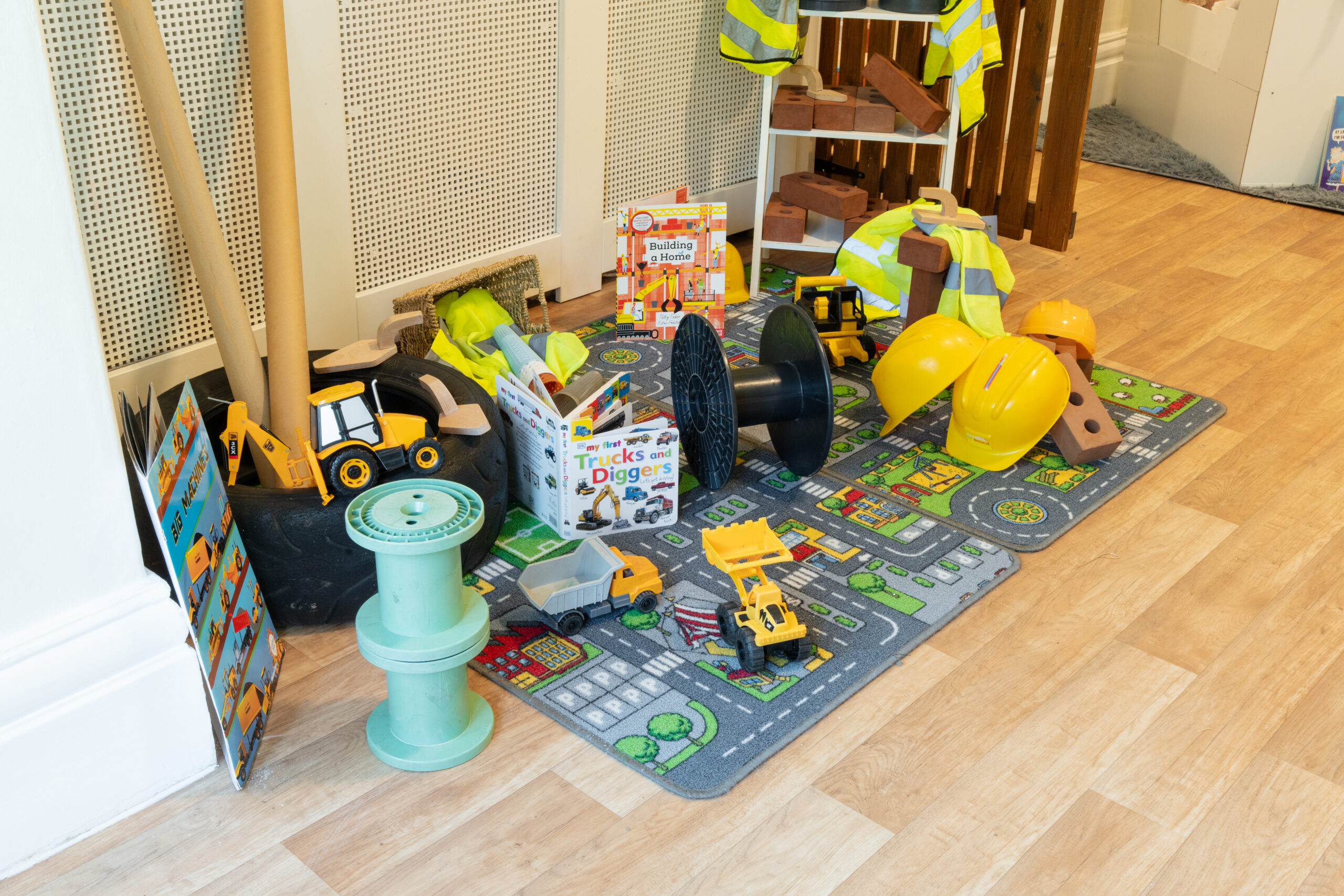 Construction vehicle toys, foam bricks and books about diggers on a road printed rug at Safehands nursery in Harrogate