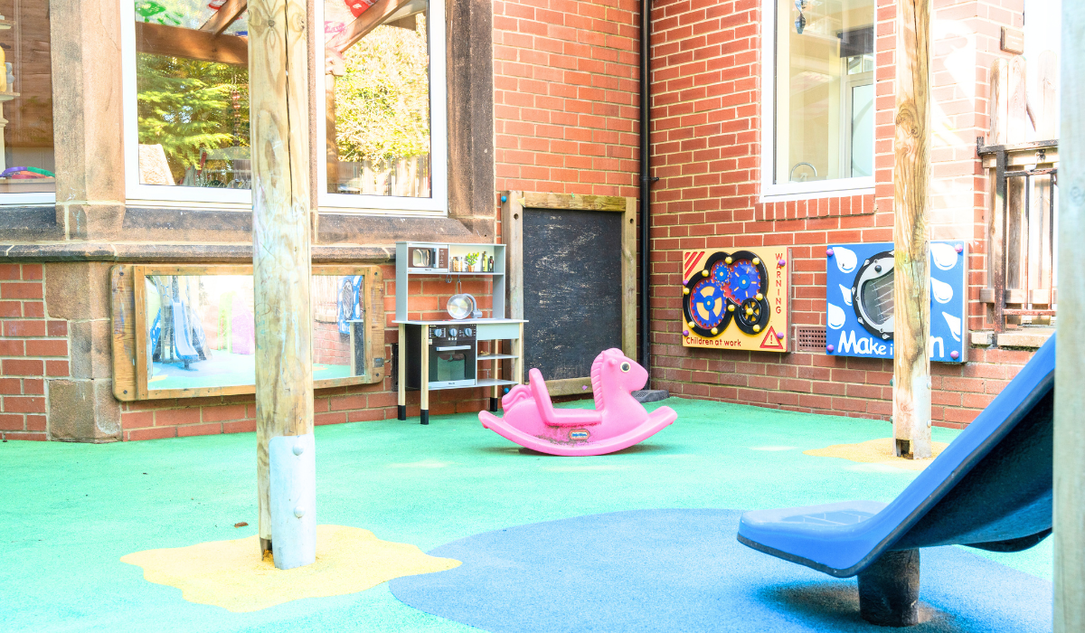 Outdoor play area at Safehands nursery and pre-school in Harrogate with rocking toy, outdoor kitchen and sensory exploration toys