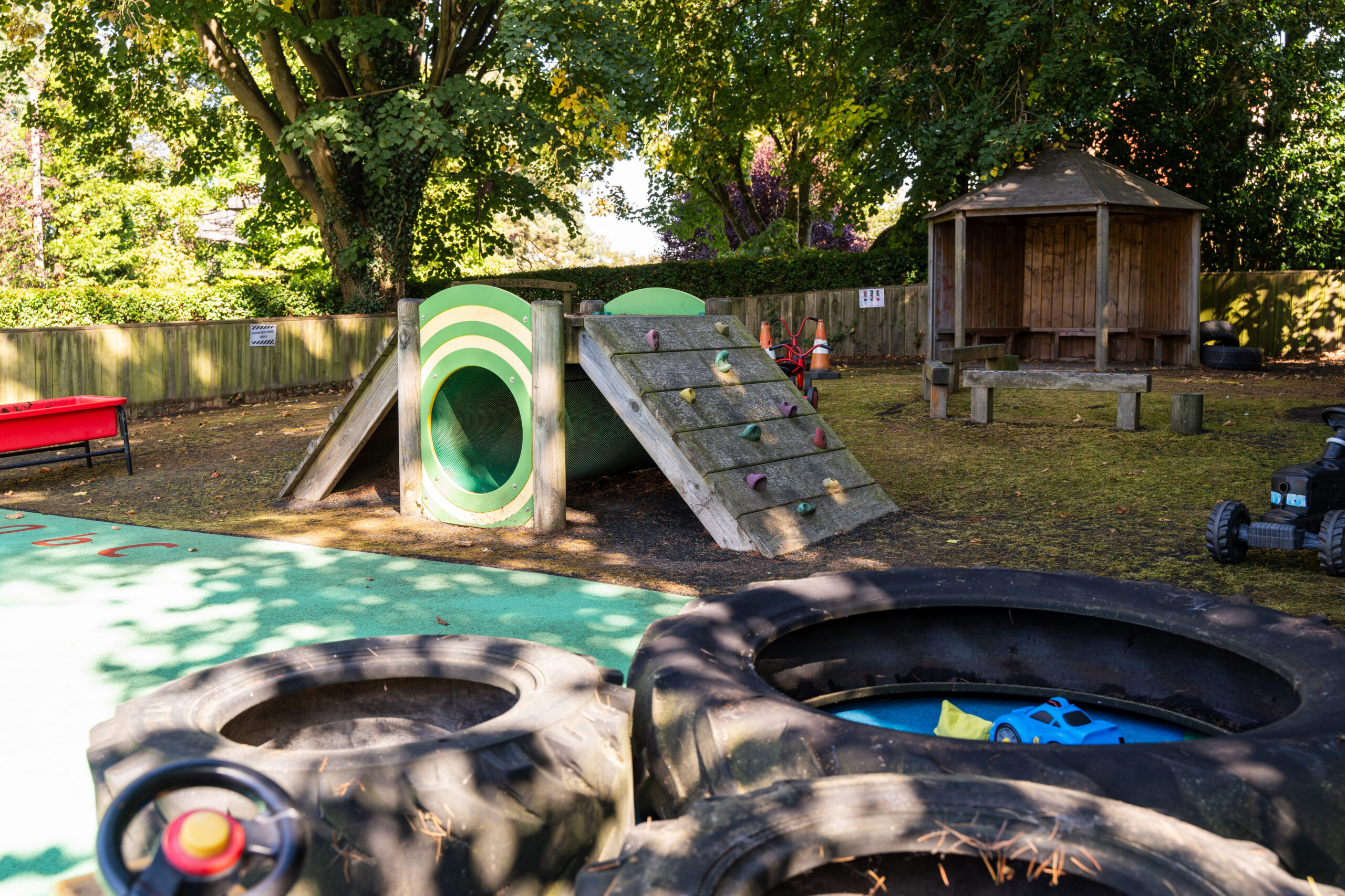 Wooden climbing frame with tunnel in the outdoor area at Safehands nursery in Harrogate
