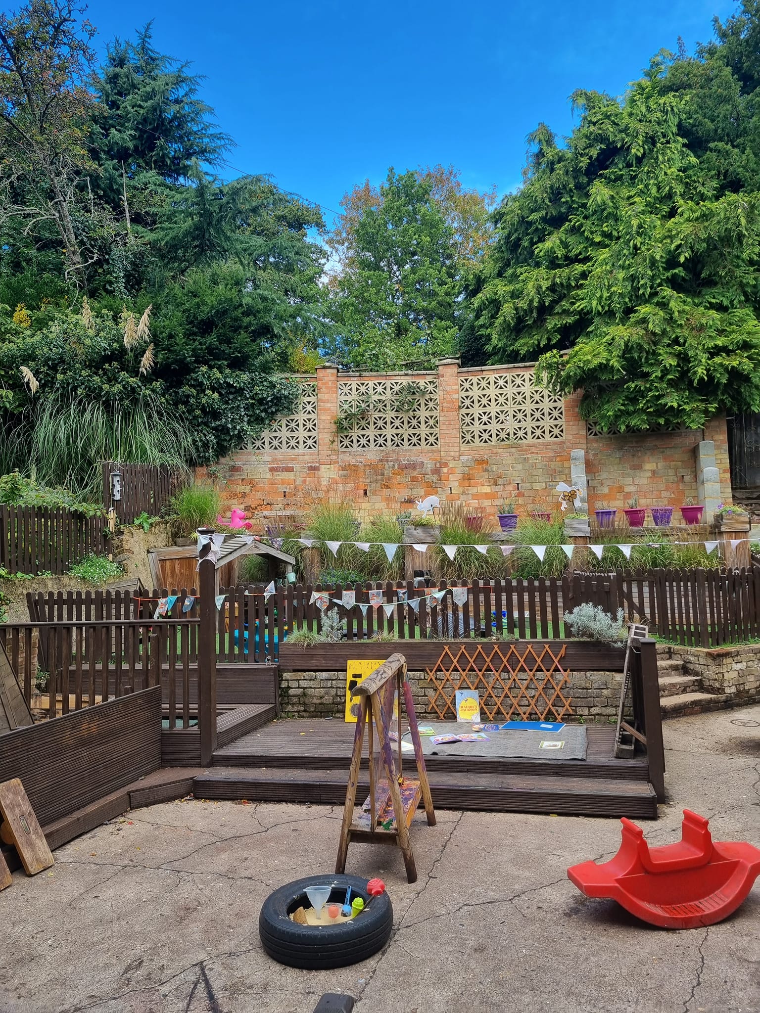 Outdoor play area with decking, grass and bunting at Sycamore House nursery in Bishop