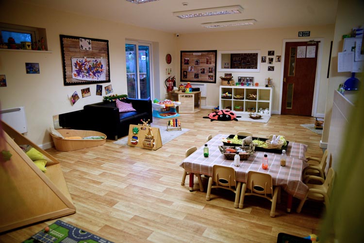 Wooden chairs and tables with a sofa in the background at Partou Acorns in Adel nursery in Leeds