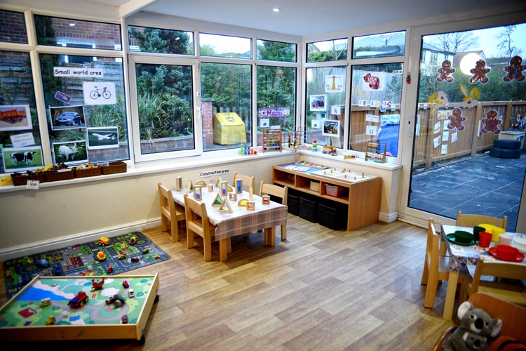 Table and chairs with activities set up in a bright airy room next to a large window at Partou Acorns in Adel nursery and pre-school in Leeds