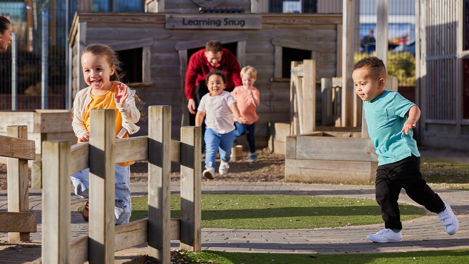 Young children running in an outside nursery play area
