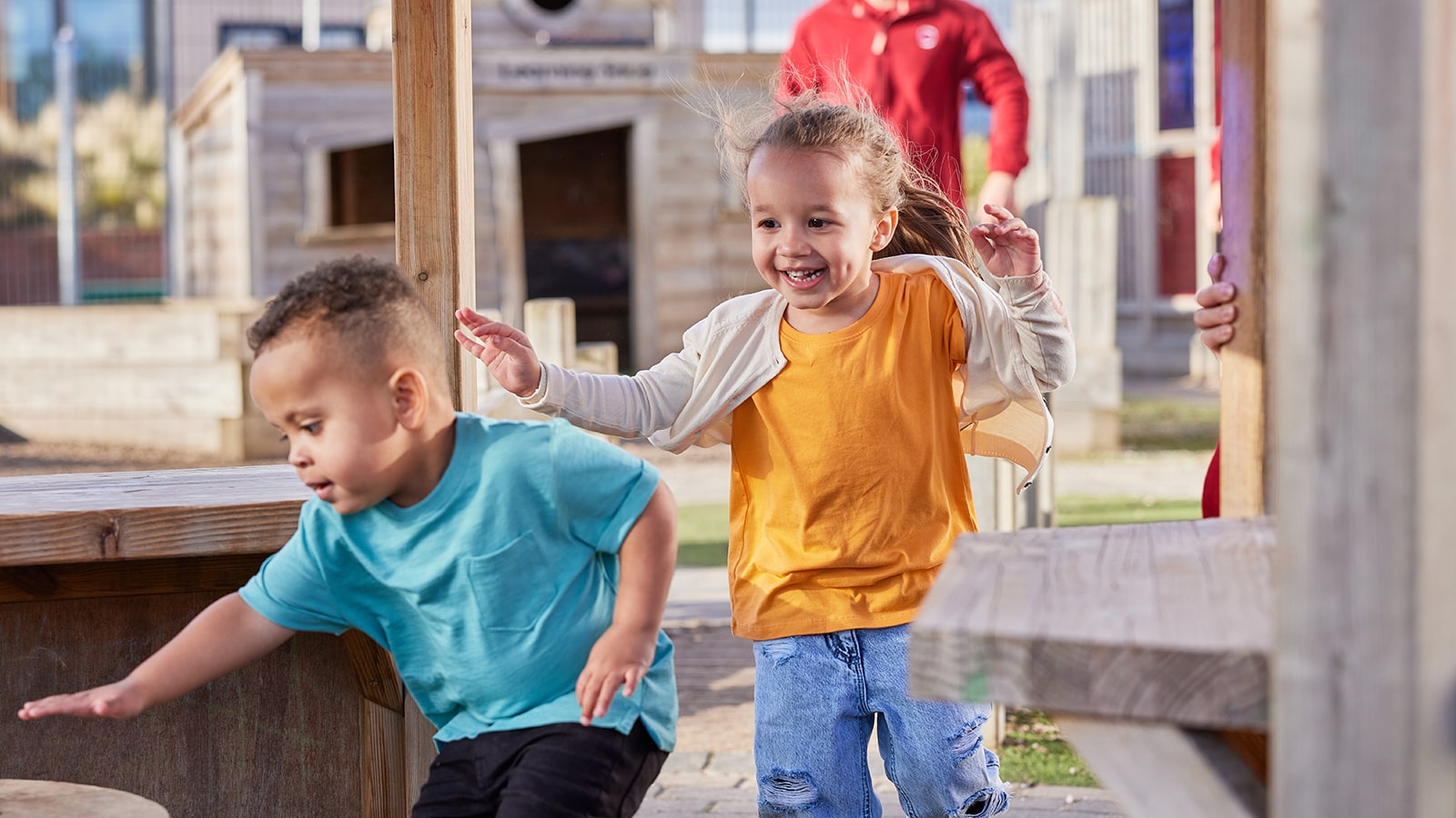 Young girl in yellow T-shirt chasing boy in blue T-shirt outside
