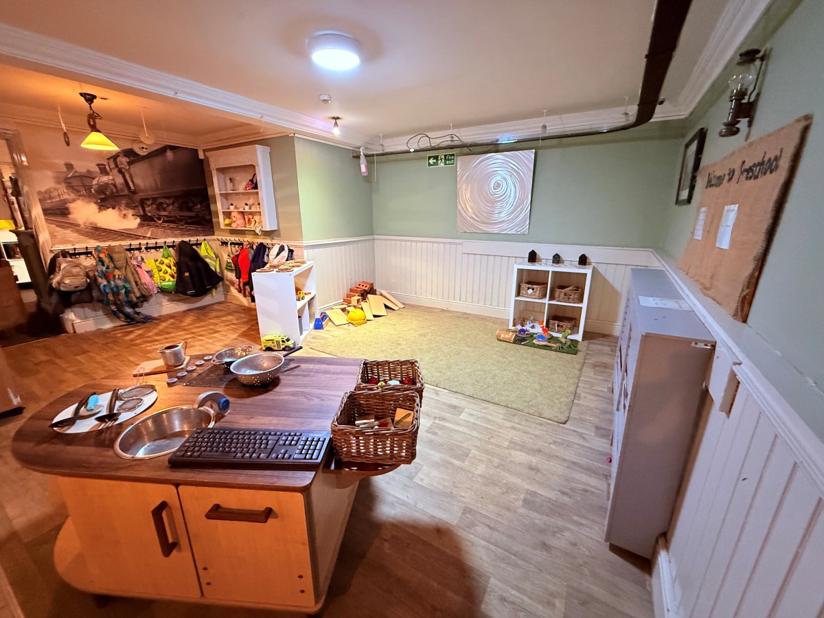 Preschool room at Partou The Railway Euxton Day Nursery with play kitchen, coat area and inviting carpeted play space