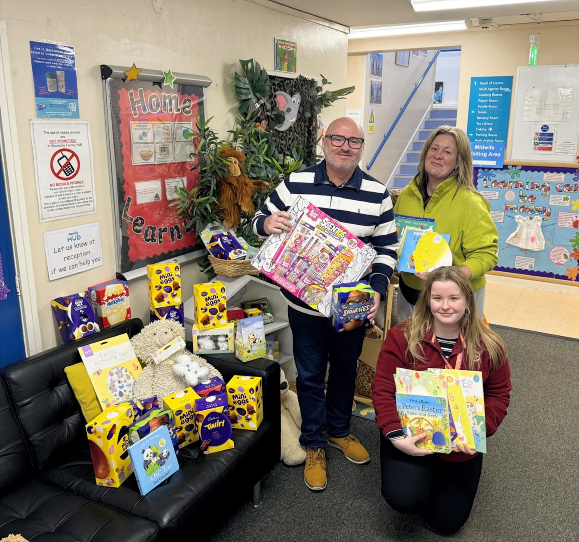 Partou Childcare team members pose with Easter donations including books, chocolate eggs and gifts during a presentation to the local charity Home‑Start Manchester.