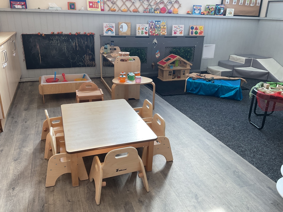 Inspiring early years learning environment at Partou Parbold Day Nursery & Pre-school, featuring natural timber play furniture, a glowing sensory table illuminated in soft purple light, colourful children
