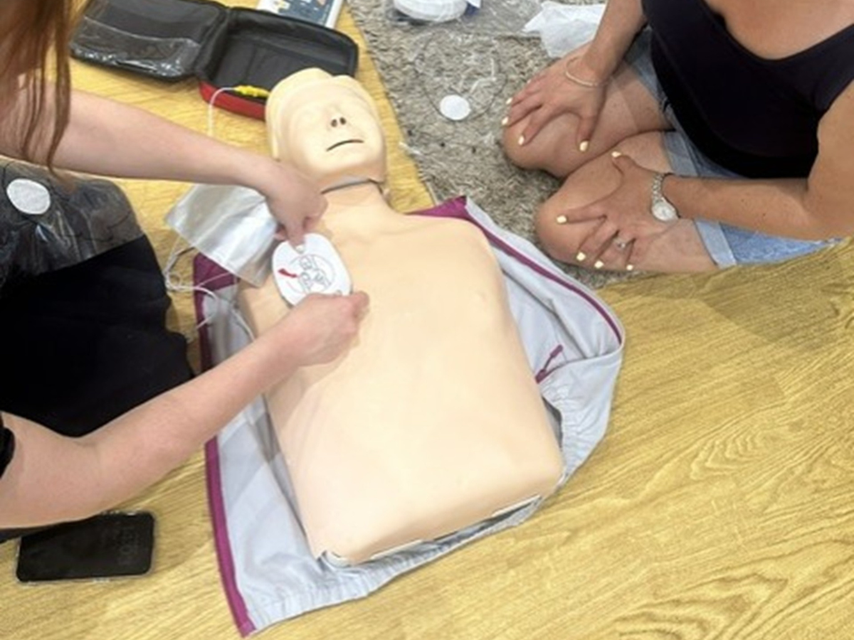Nursery team members take part in paediatric first aid training at Partou Gingerbread House Day Nursery & Pre-School, practising emergency response procedures on a CPR training manikin during a hands-on session delivered by Tigerlily Training.