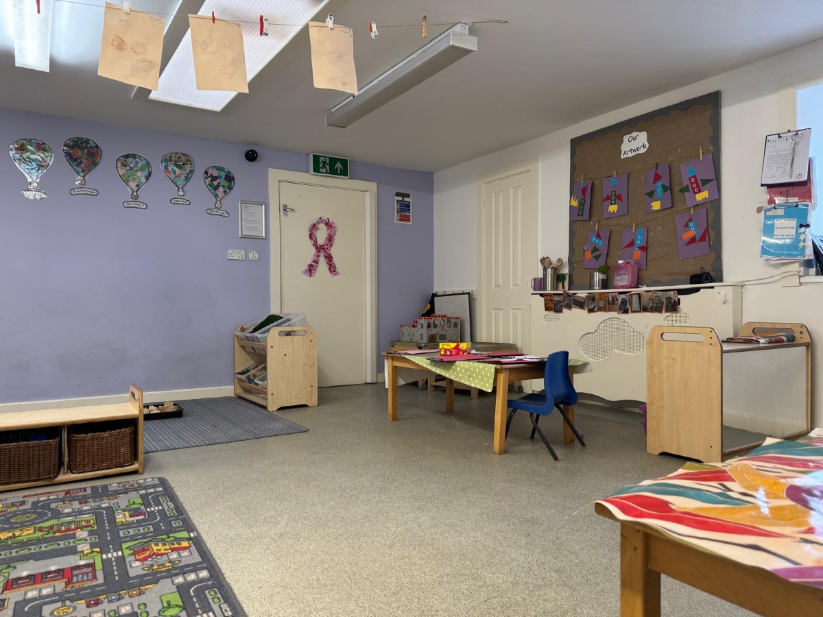 Bright early years learning environment at Partou Little Faces Day Nursery & Pre-School featuring soft lilac walls, natural wooden storage units, a creative activity table with blue chairs, colourful children