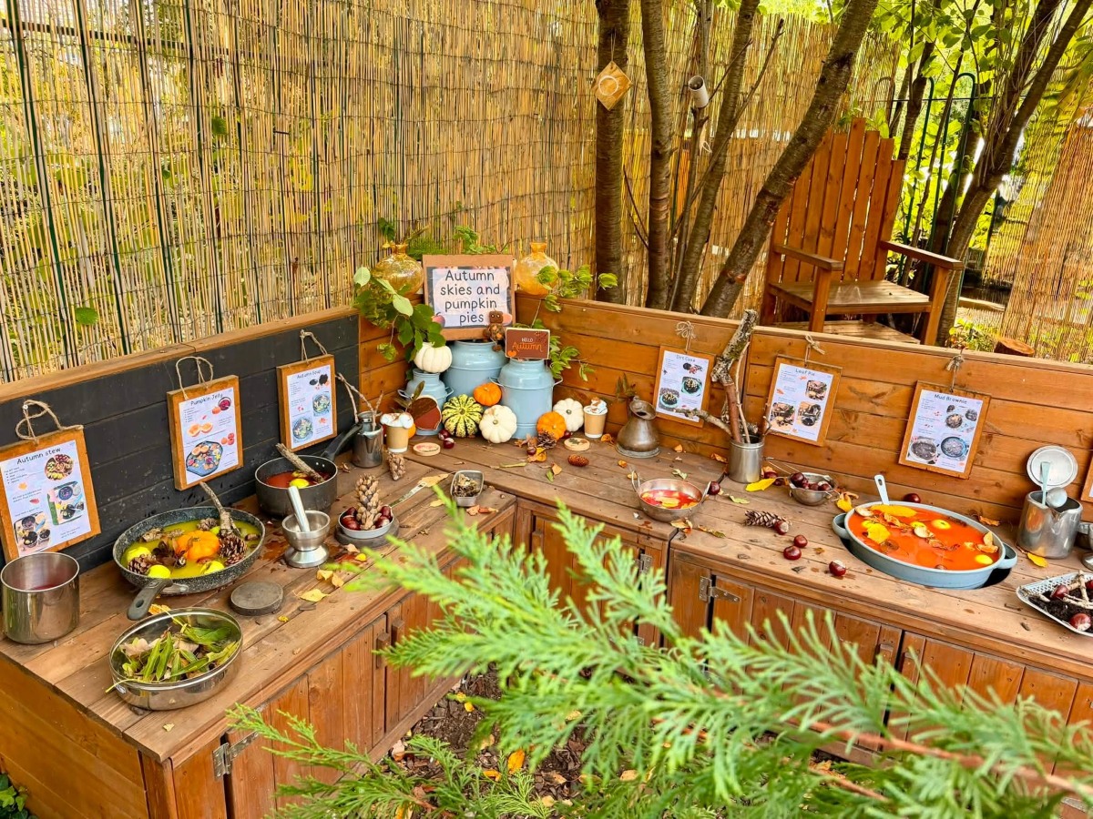 Autumn sensory play station with orange and white pumpkins, golden leaves and nature-inspired activities, encouraging outdoor learning as the clocks go back and the seasons change.