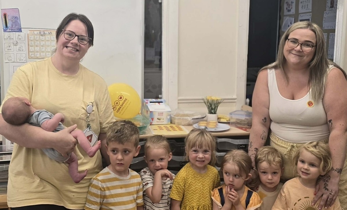 Children and nursery team members at Partou Habergham Day Nursery celebrating a Yorkshire Air Ambulance fundraising event, dressed in yellow and gathered together in the nursery classroom.