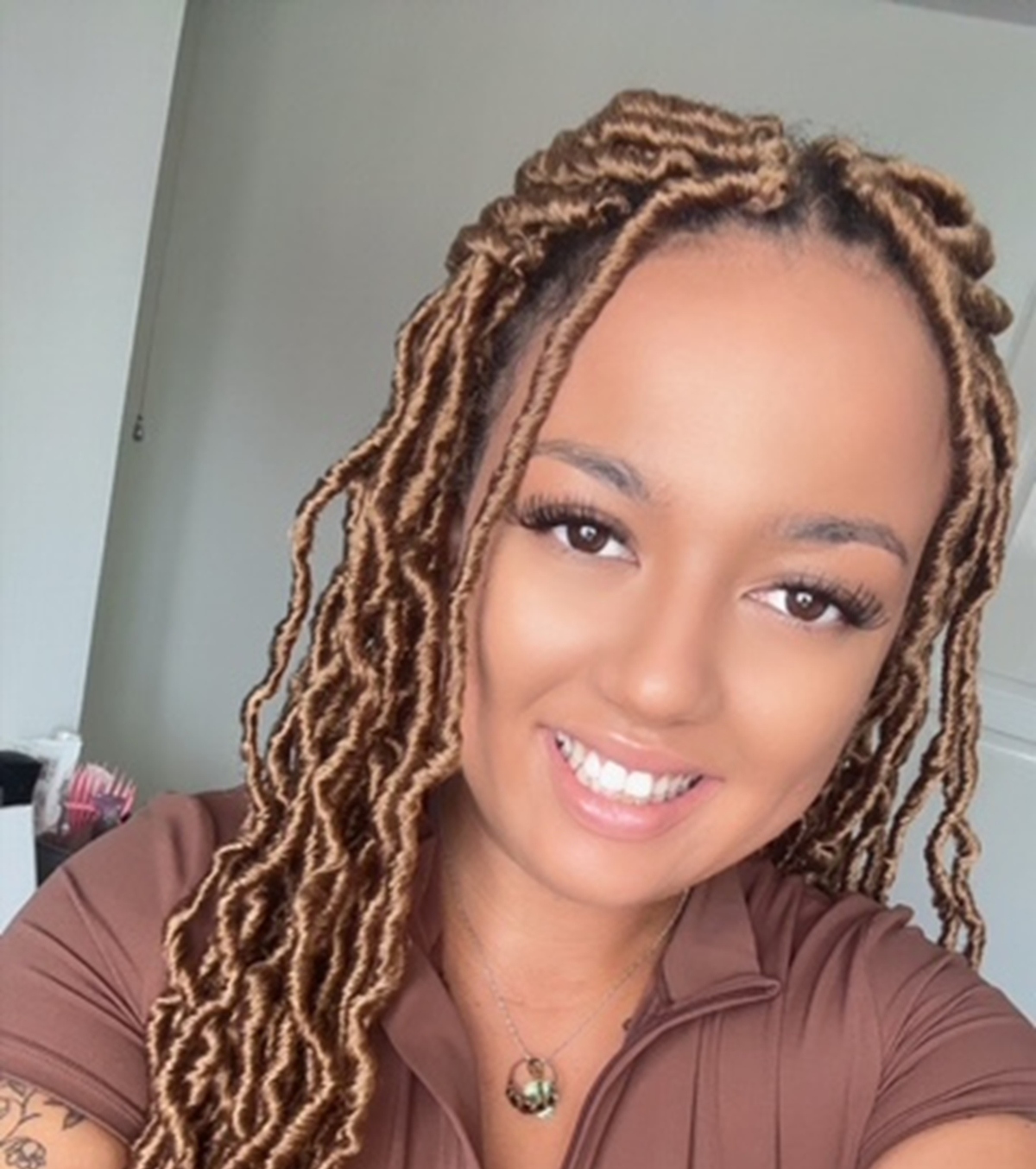 Mel Fitzpatrick who is Nursery Manager at Partou Best Friends Day Nursery & Pre-School. Mel is wearing a brown zip top and has long black eyelashes. Mel has beautiful long blonde and brown braids.